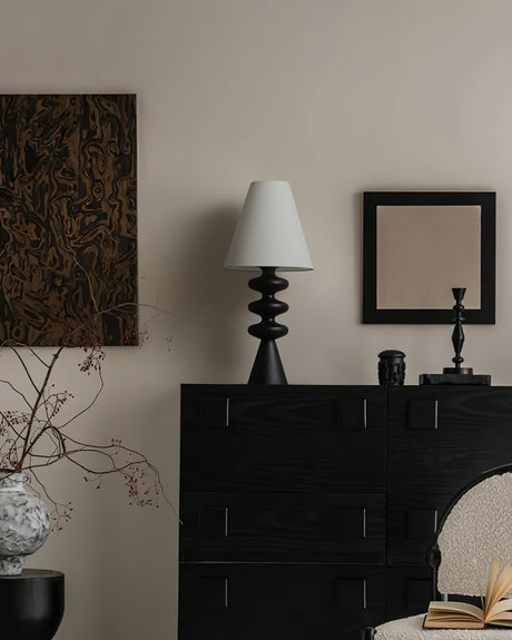 Rippled base lamp unlit on a dark cabinet in a pale living room