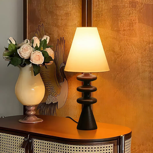 Rippled base lamp lit on a curved console beside a ceramic vase