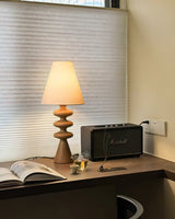Rippled base lamp lit on a desk beside an open book and a speaker