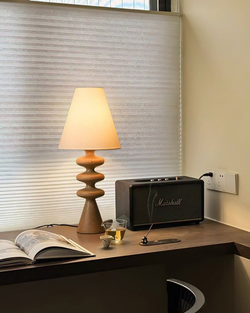 Rippled base lamp lit on a desk beside an open book and a speaker