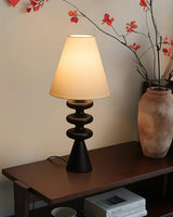 Rippled base lamp lit on a console beside branches in a stone vase