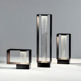 The three sizes lit together on a pale floor beside a studio wall