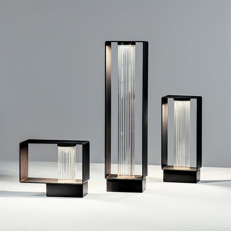 The three sizes lit together on a pale floor beside a studio wall