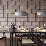 Two gray honeycomb pendants above a long dining table set for a meal