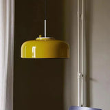 Yellow pendant lamp lit at dusk beside a dark green wall