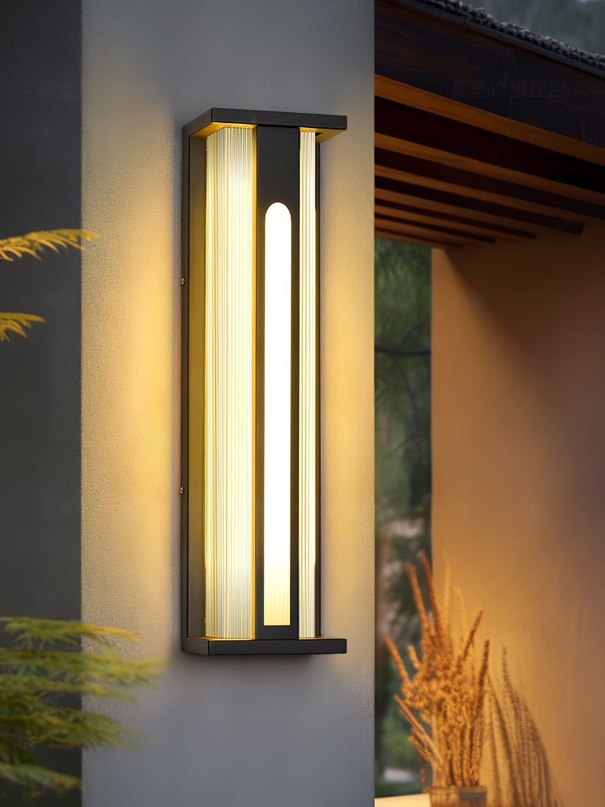 The light lit at the corner of a house wall with grass and a hedge