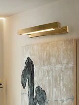 Brass bar lit over a wide textured canvas on a pale wall in a quiet room