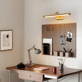 Gold bar lit above a walnut desk with a task lamp, a camera and a pegboard