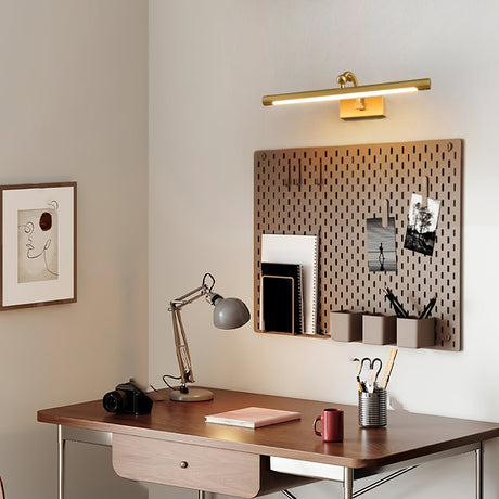 Gold bar lit above a walnut desk with a task lamp, a camera and a pegboard