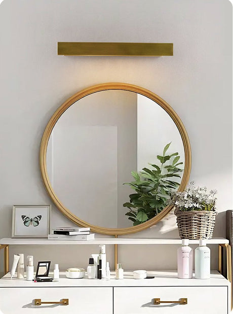 Brass bar above a round mirror over a white vanity with open drawers