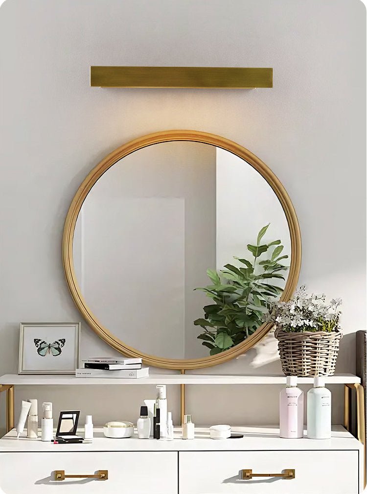 Brass bar above a round mirror over a white vanity with open drawers