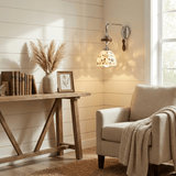 The sconce with a patterned shade above a wood console and a cream armchair