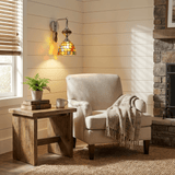 The mosaic sconce above a wood side table and an armchair beside a stone fireplace
