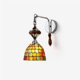 Wall sconce with a colorful mosaic dome shade hanging from a chrome arm with a walnut handle