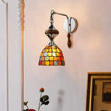 The mosaic shade lit on a pink wall beside white molding and a gilt frame