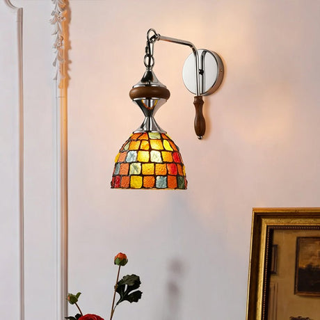 The mosaic shade lit on a pink wall beside white molding and a gilt frame