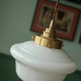 Close view of the knurled brass socket holding the opal shade below a framed picture