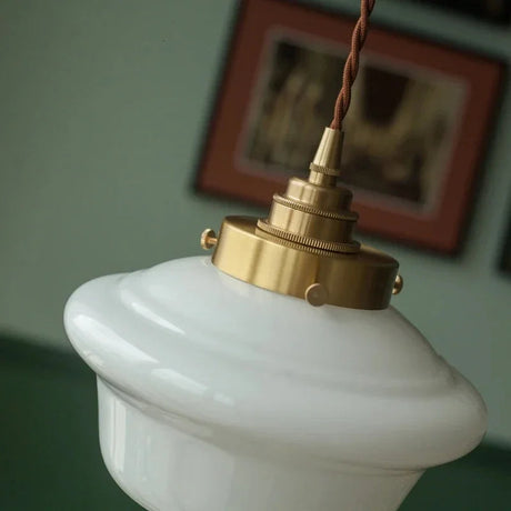 Close view of the knurled brass socket holding the opal shade below a framed picture