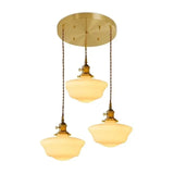 Three opal shades hung close together from one round brass ceiling plate