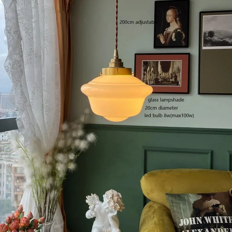 The shade lit beside a curtained window above a yellow armchair and dried flowers