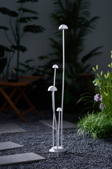 The tallest cap lit above the shorter ones against dark planting