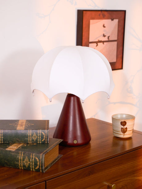 Nightstand lamp unlit beside a stack of green bound books