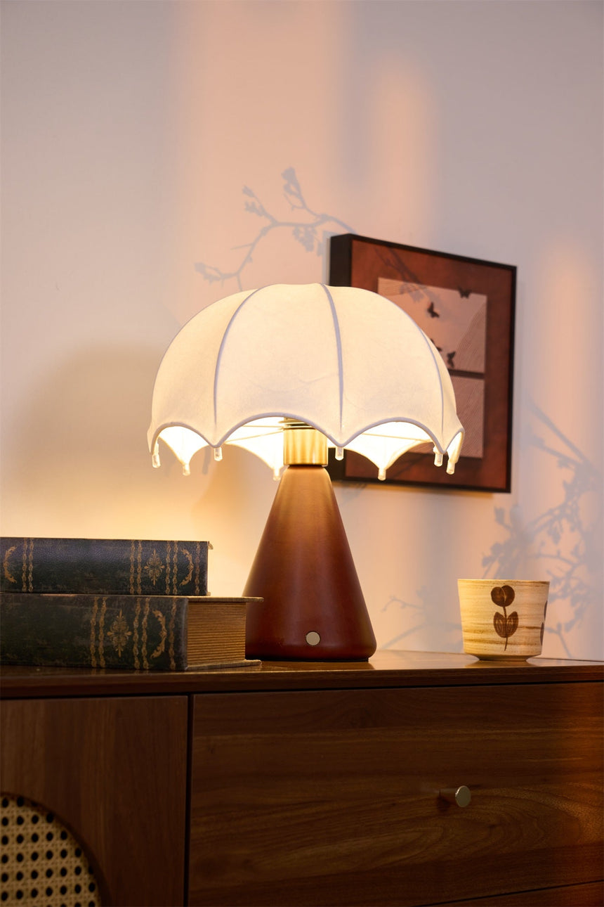 Nightstand lamp lit beside a small framed picture on a dresser