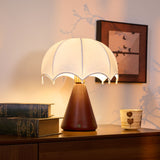 Nightstand lamp lit warm on a dresser beside a patterned cup