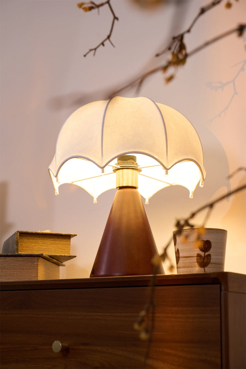 Nightstand lamp lit beside dried branches and a ceramic cup