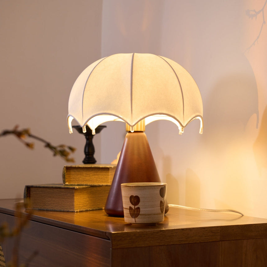 Nightstand lamp lit on a walnut dresser beside old bound books