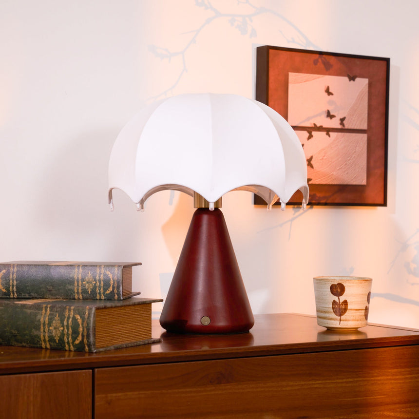 Nightstand lamp unlit on a dresser beside a framed print