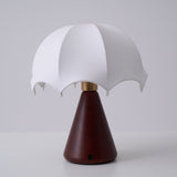 Nightstand lamp unlit against a plain gray ground, seen front on