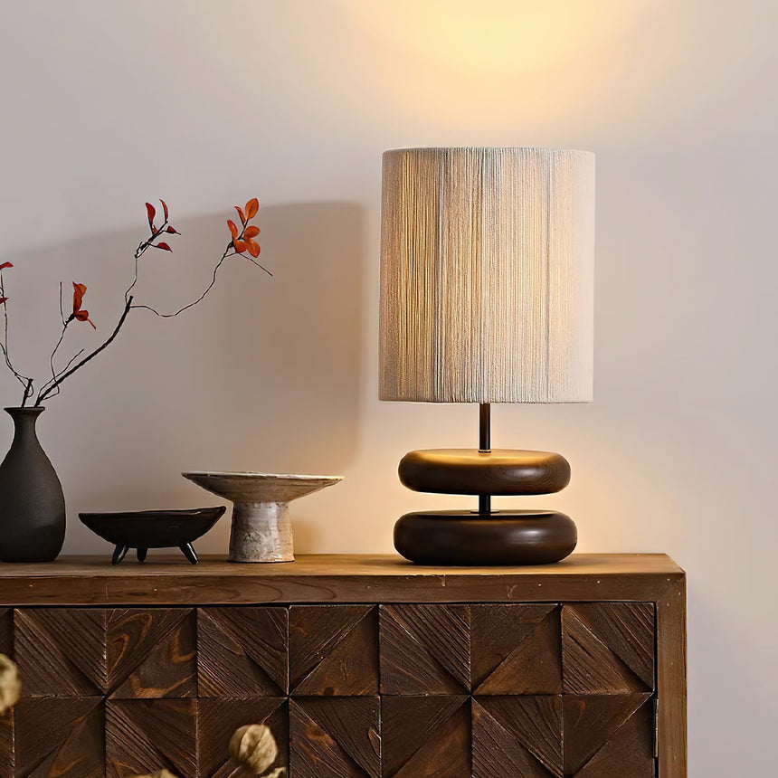 Black pebble nightstand table lamp lit on a wooden sideboard