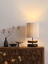 Black pebble nightstand table lamp switched on beside a vase