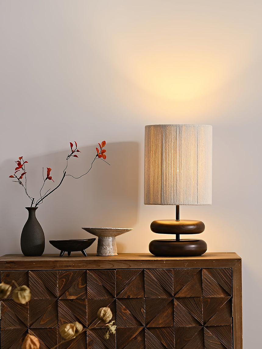 Black pebble nightstand table lamp switched on beside a vase