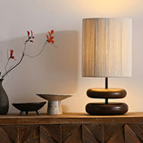 Black pebble nightstand table lamp beside a branch in a dark vase