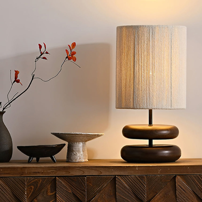 Black pebble nightstand table lamp beside a branch in a dark vase