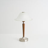 Nightstand table lamp seen from the front against a plain pale ground