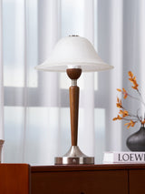 Nightstand table lamp lit on a nightstand against a pale wall