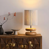 Nightstand table lamp lit on a sideboard beside a branch in a vase