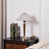 Nightstand table lamp lit on a dark nightstand beside stacked books