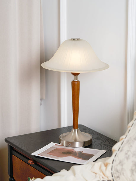 Nightstand table lamp lit on a nightstand beside a white pillow