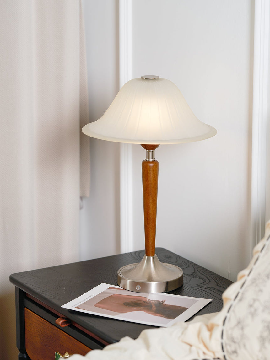 Nightstand table lamp lit on a nightstand beside a white pillow