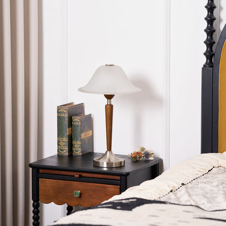 Nightstand table lamp lit on a nightstand in a pale wood trimmed bedroom