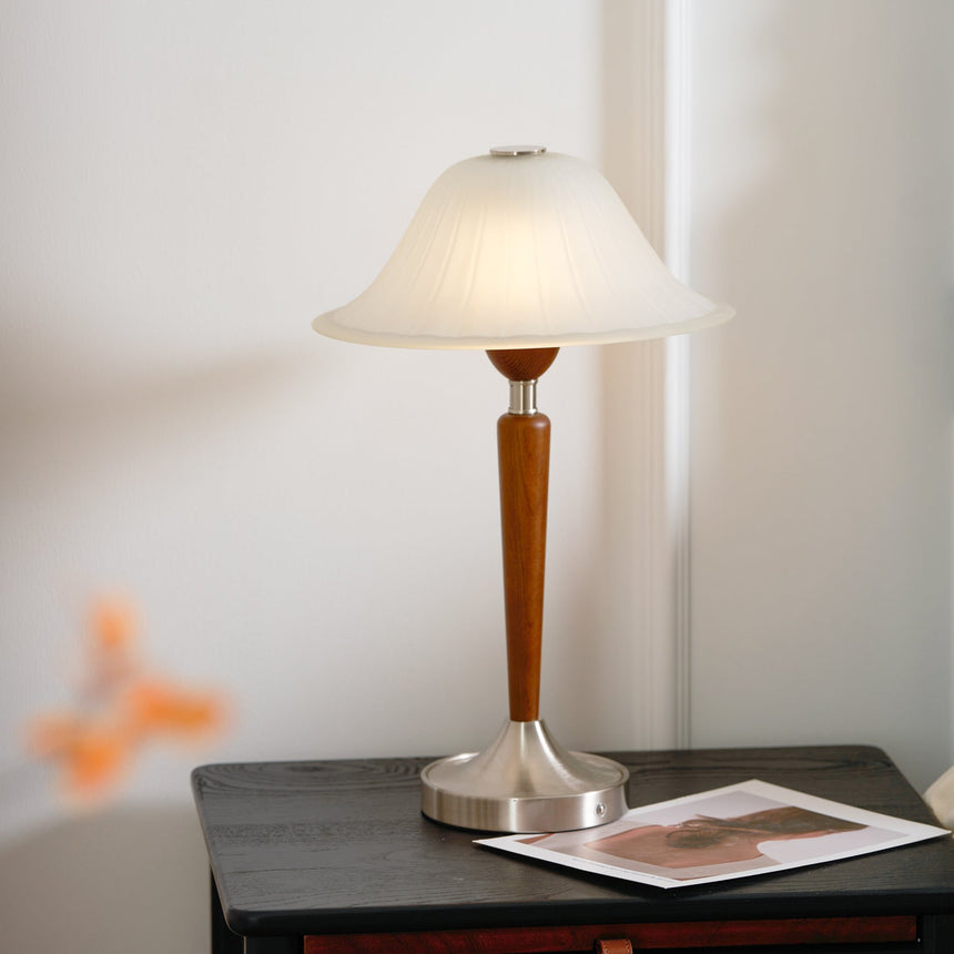 Nightstand table lamp lit on a dark painted nightstand beside a photo