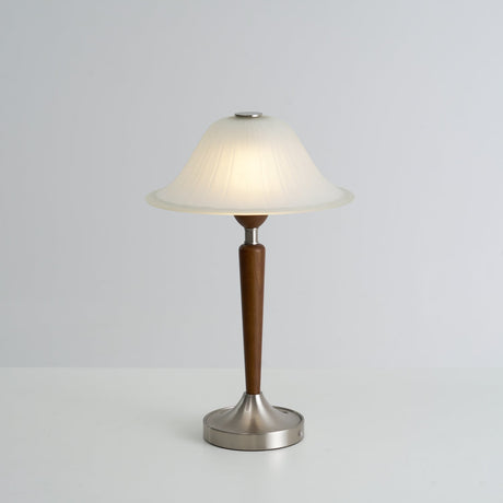 Nightstand table lamp lit and seen in full against a plain ground