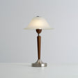 Nightstand table lamp lit in a warm tone against a plain ground