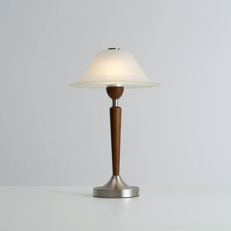 Nightstand table lamp lit in a warm tone against a plain ground