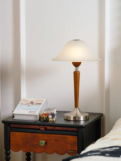 Nightstand table lamp lit beside an open book on a dark nightstand