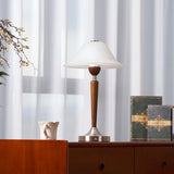 Nightstand table lamp lit on a chest beside a small dark vase
